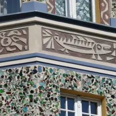 Fasada budynku zdobiona mozaiką z kolorowego szkła i sgraffito przedstawiającym rybę.