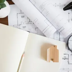Wypis i wyrys z rejestru gruntów, plany architektoniczne, lupa i drewniany domek.