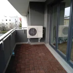 Klimatyzacja w bloku zamontowana na balkonie. Jednostka zewnętrzna chłodzi mieszkanie, a widok na sąsiednie budynki zapewnia relaks.