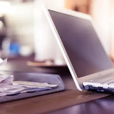 Laptop i sterta rachunków na biurku.