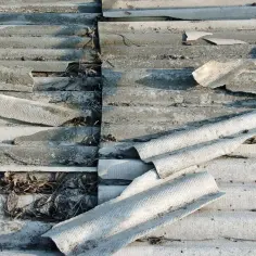 Zniszczone eternitowe pokrycie dachowe z widocznymi fragmentami azbestu.