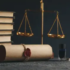 Stos książek, waga sprawiedliwości, zwój z pieczęcią, kałamarz i pióro.