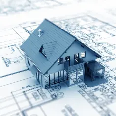Model domu na planach architektonicznych, ilustrujący etapy budowy domu od projektu do realizacji.