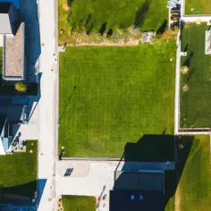 Widok z lotu ptaka na osiedle domów jednorodzinnych z zadbanymi ogrodami. Widać tu różne projekty architektoniczne, a także panele słoneczne na dachach. Całkowita powierzchnia budynku jest starannie zagospodarowana.