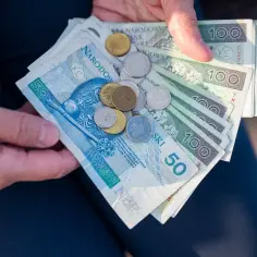 Dłonie trzymają polskie banknoty i monety. Ile razy można dać darowiznę dziecku? Zależy od kwoty i Twojej hojności.