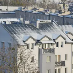 Dachy bloków mieszkalnych pokryte śniegiem, widok z góry.