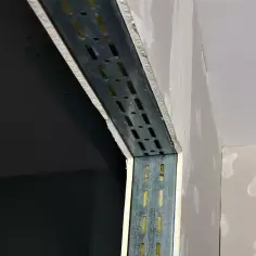 Fragment metalowego profilu konstrukcyjnego z otworami, obłożony płytą gipsowo-kartonową.