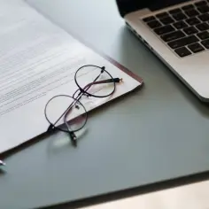 Okulary na dokumencie z tekstem, obok laptopa. Czas na podpisanie umowy dzierżawy.