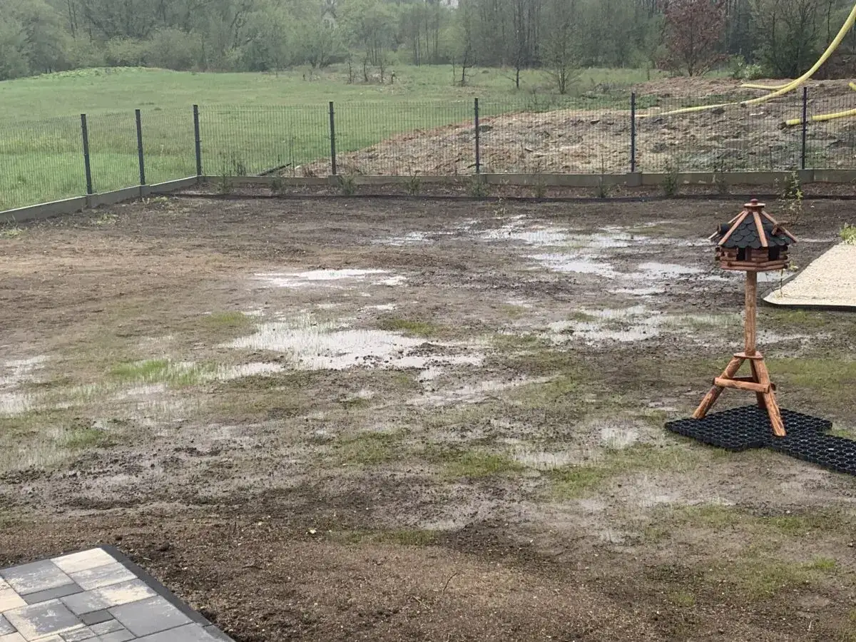 Po ulewnym deszczu teren wymaga melioracji. Widać kałuże i błoto na nowo przygotowanym pod trawnik placu.