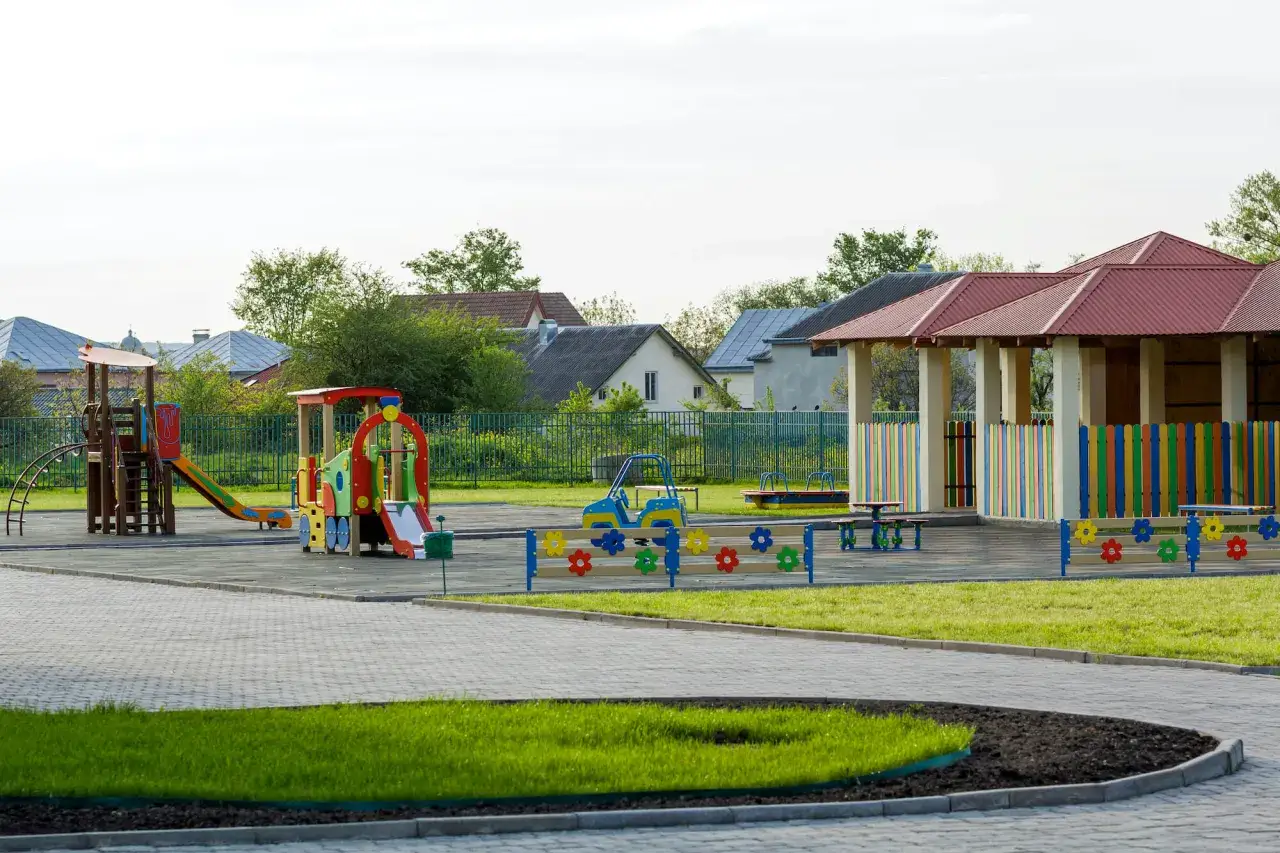 Kolorowy plac zabaw z domkami i zjeżdżalniami. Czy plac zabaw wymaga pozwolenia na budowę? To zależy od jego wielkości i konstrukcji.